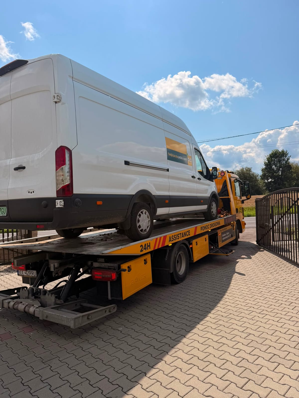 Holowanie busa kurierskiego Ford Transit na lawecie w słoneczny dzień